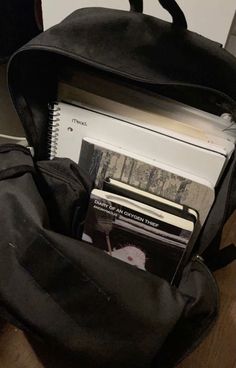 a black backpack filled with books on top of a wooden table