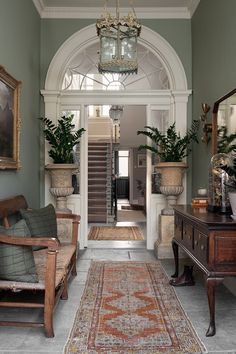 an entry way with green walls and white trim, wooden furniture and potted plants