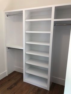 an empty closet with white shelves and wooden floors