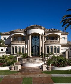 a large white house with palm trees in the front yard