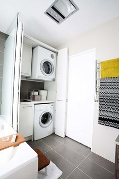 a washer and dryer in a small room with tile flooring on the walls