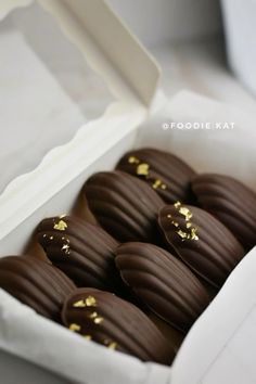 chocolate covered cookies in a white box with gold sprinkles