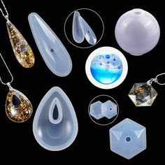 an assortment of jewelry is displayed on a black surface with white and gold accents, including pendants