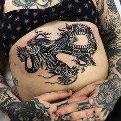 a woman with tattoos on her stomach holding a dragon tattoo in front of her belly