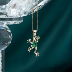 a gold pendant with a green stone frog on it