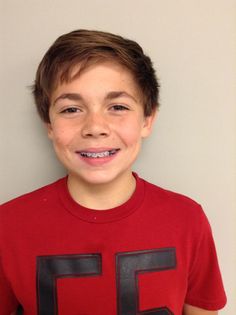 a young boy wearing a red shirt with black letters on it