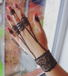 a woman's hand with hennap and bracelets on her wrist, in front of a window