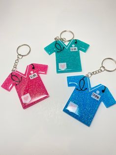 three key chains with different colored shirts on them