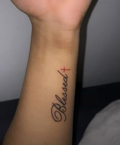 a woman's wrist with a cross and the word fearless tattooed on her arm