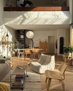 a living room filled with furniture next to a stair case above a table and chairs