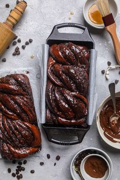 two loafs of chocolate cake sitting on top of a counter next to bowls and spoons