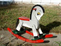 a wooden rocking horse sitting in the grass