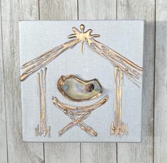 a nativity scene made out of wood and metal on a white canvas with gold accents