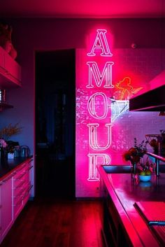 a pink neon sign is lit up in the kitchen