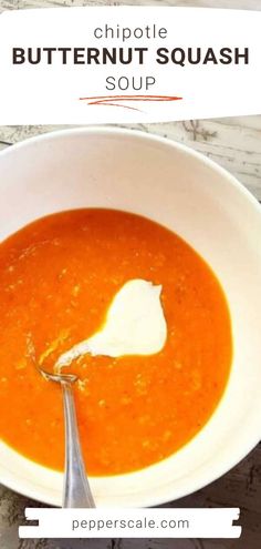 a white bowl filled with carrot soup on top of a marble counter next to a spoon