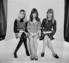 three women sitting next to each other on a white background