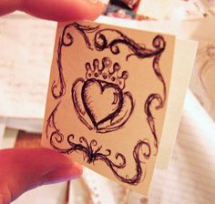 a hand holding up a piece of paper with a heart and crown drawn on it