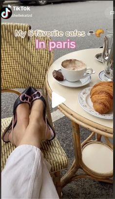 a person's feet resting on a table with coffee and croissants