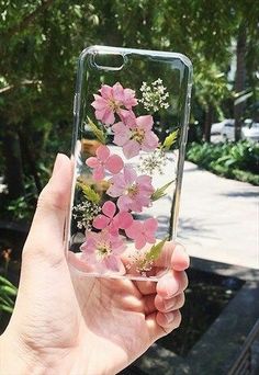 a hand holding up a clear case with pink flowers on the front and back cover