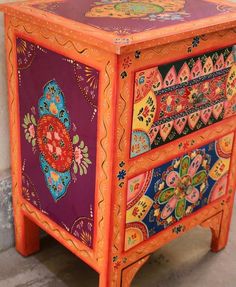 an orange and purple painted dresser with flowers on it