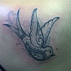 a woman's chest with a bird tattoo design on the back of her shoulder