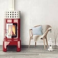 a red stove sitting next to a chair in a room with white walls and wood floors