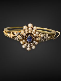 "This magnificent bracelet bangle dates back to the Victorian era. It is crafted in 14K gold. Centered with a natural vivid blue sapphire, and accented with antique natural pearls, and diamonds. Bracelet Circumference: 7.0\" Approximate Carat Weight of Sapphire: 0.60 Carats Approximate Carat weight of Diamond: 0.85 carats Smallest Measurement of Pearl: 1.5 mm x 1.5 mm Largest Measurement of Pearl: 4.0 mm x 4.0 mm Weight: 23.7 grams Metal Purity: 14KT Gold" Victorian Jeweled Wedding Bracelets, Heirloom Jeweled Wedding Bracelets, Heirloom Jeweled Bracelets For Wedding, Yellow Gold Jeweled Bracelet For Formal Occasions, Jeweled Yellow Gold Bracelets For Formal Occasions, Elegant Jeweled Yellow Gold Bracelet, Victorian Jeweled Bracelets For Formal Occasions, Yellow Gold Jeweled Bracelets For Formal Occasions, Formal Yellow Gold Jeweled Bracelets