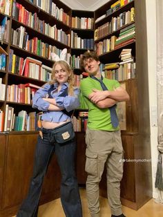 two people standing next to each other in front of a book shelf filled with books