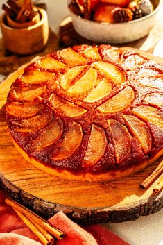 a pineapple upside down cake sitting on top of a wooden cutting board next to bowls of fruit