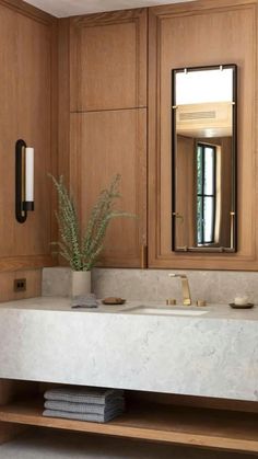 a white sink sitting under a bathroom mirror next to a wooden cabinet and counter top