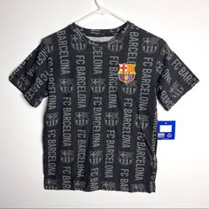 a t - shirt with the word barcelona printed on it, hanging from a hanger