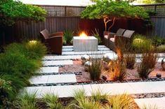 an outdoor patio with seating and firepit in the center, surrounded by plants and trees