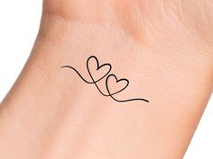 a small tattoo on the wrist of a woman with two hearts drawn on it's arm