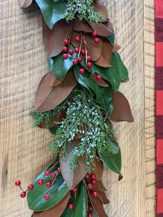 a bunch of green leaves and red berries hanging from a wooden wall with a checkered table cloth