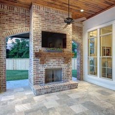 a brick fireplace with a flat screen tv above it in the middle of a patio