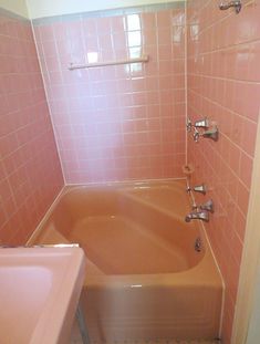 a bathtub and sink in a bathroom with pink tiles