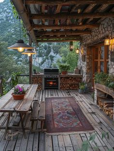 an outdoor kitchen and dining area on a wooden deck with stone walls, potted planters and grill in the center