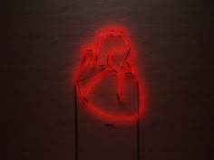 a red neon heart on a black brick wall