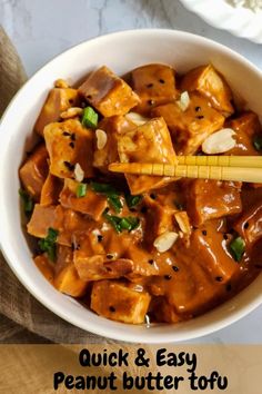 a white bowl filled with tofu and green onions next to chopsticks in it