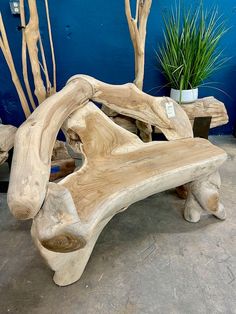 a wooden bench made out of driftwood in front of a blue wall with potted plants