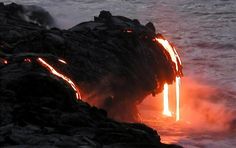 lava pouring out of the ocean into the water at night with bright orange light coming from it