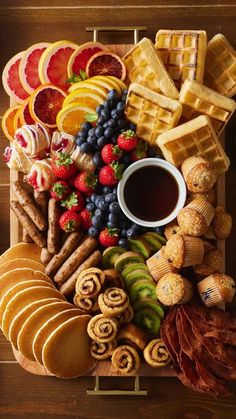 a platter filled with different types of snacks and fruit on top of a wooden table