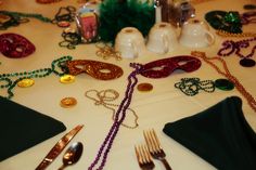 a table topped with lots of different types of masks and silverware on top of a white table cloth