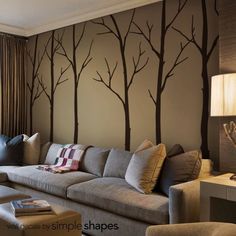 a living room with couches, lamps and trees painted on the wall behind it