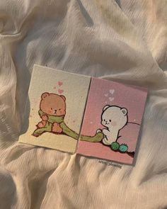 two small cards with teddy bears on them sitting on a white bed sheet, next to each other