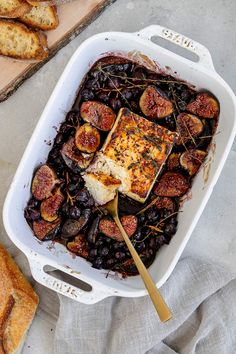 a casserole dish with figs and bread on the side, ready to be eaten