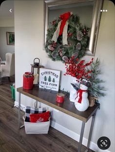 a christmas wreath is hanging on the wall next to a table with presents and decorations