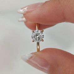 a close up of a person holding a ring with a diamond in it's middle