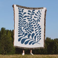 a person standing in front of a large blue and white blanket with leaves on it