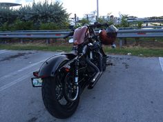 a black motorcycle parked in a parking lot next to a road with trees and bushes